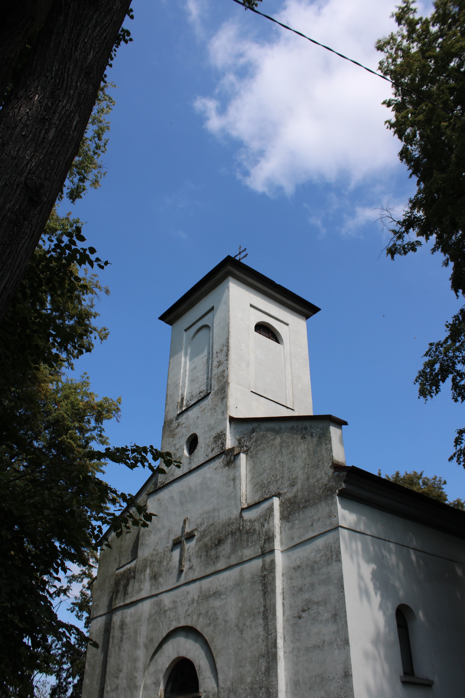 A church in desperate need of power washing. Photo is framed by trees.