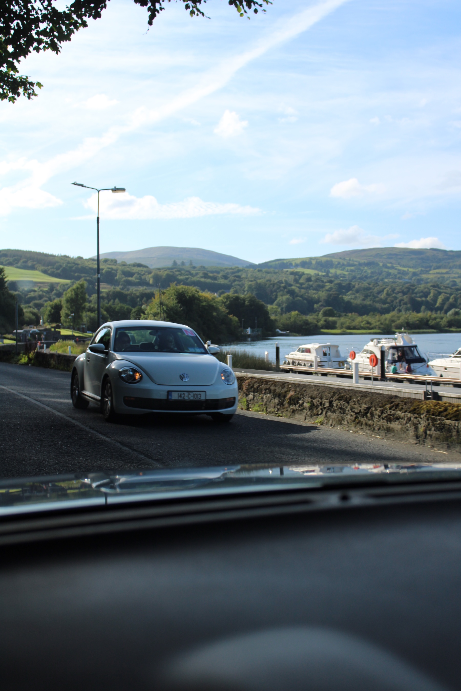 VW Beatle driving on road with view of river and mountains
