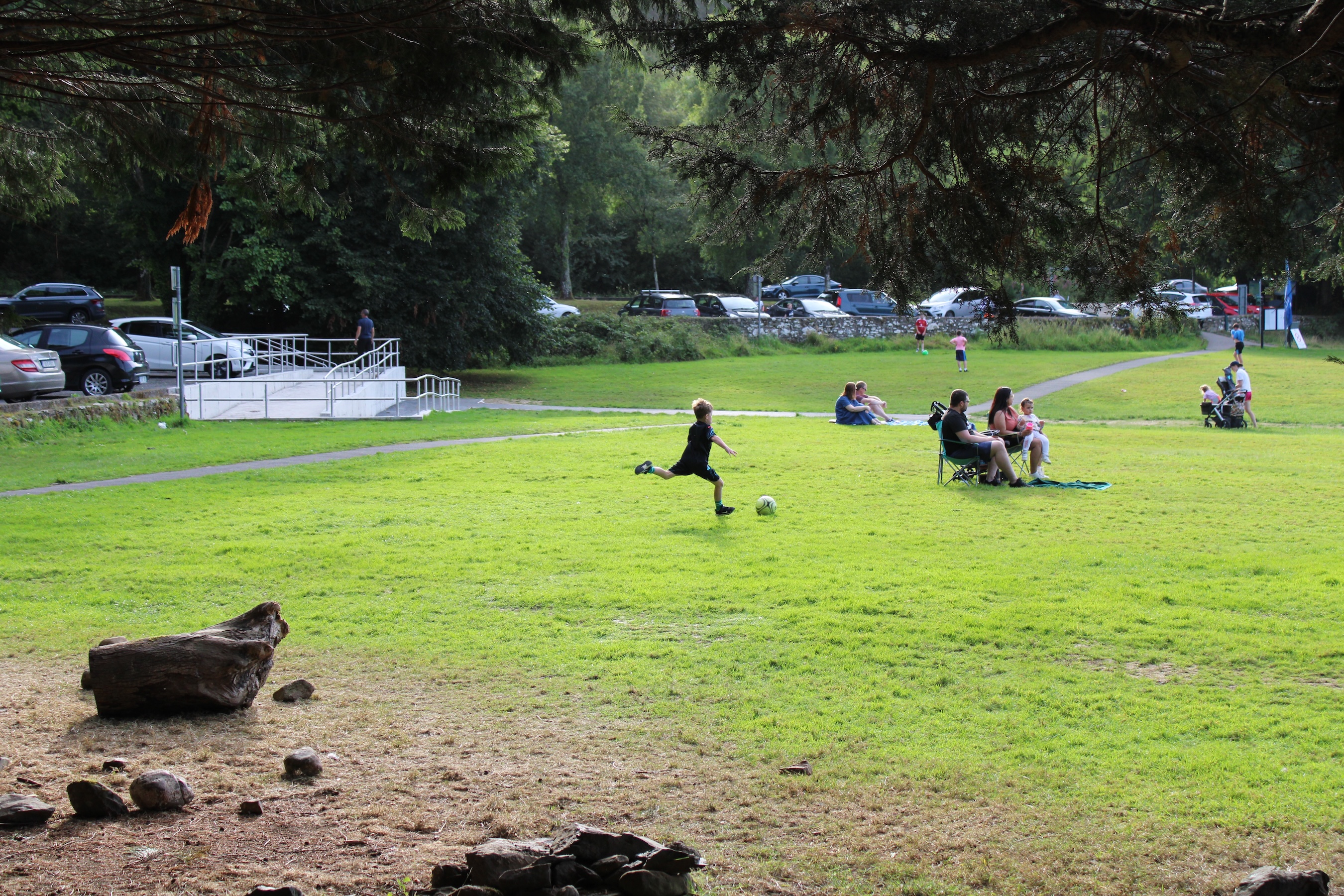 A kid is about to kick a soccer ball across a big green lawn