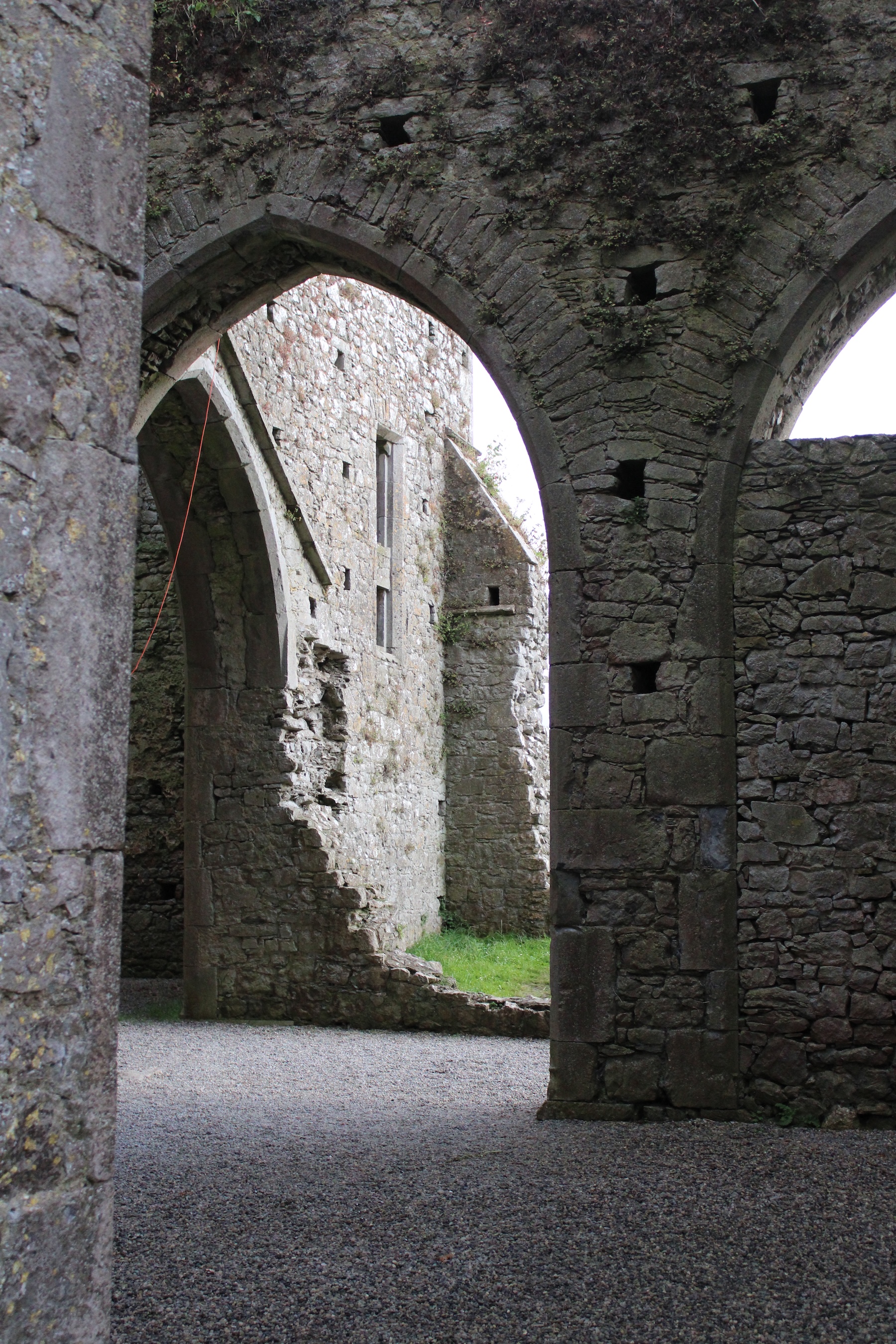 An archway casting a shadow on the gravel