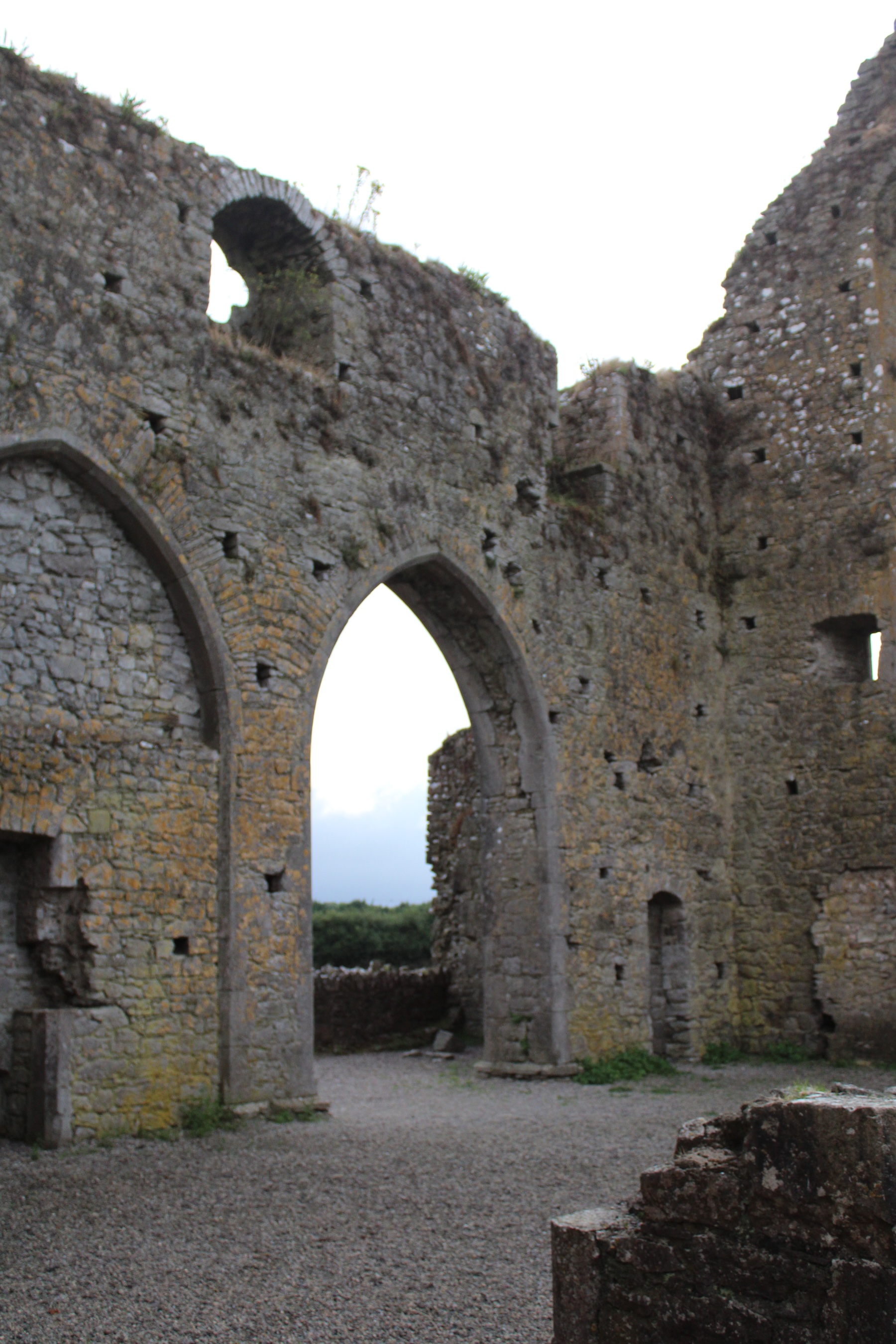 An archway alongside a wide wall of a ruin of a castle