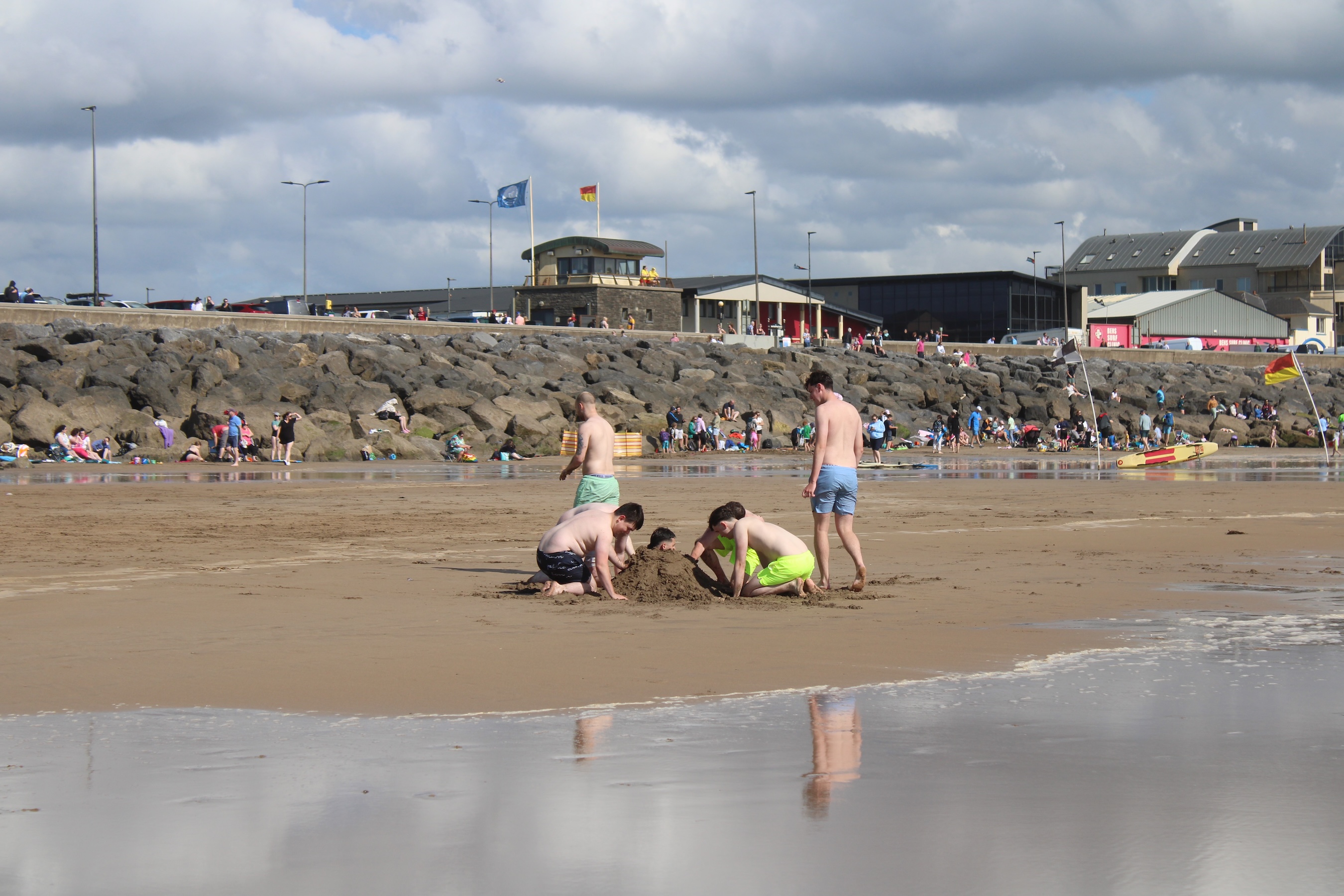 Boys bury their friend in the sand on the beach