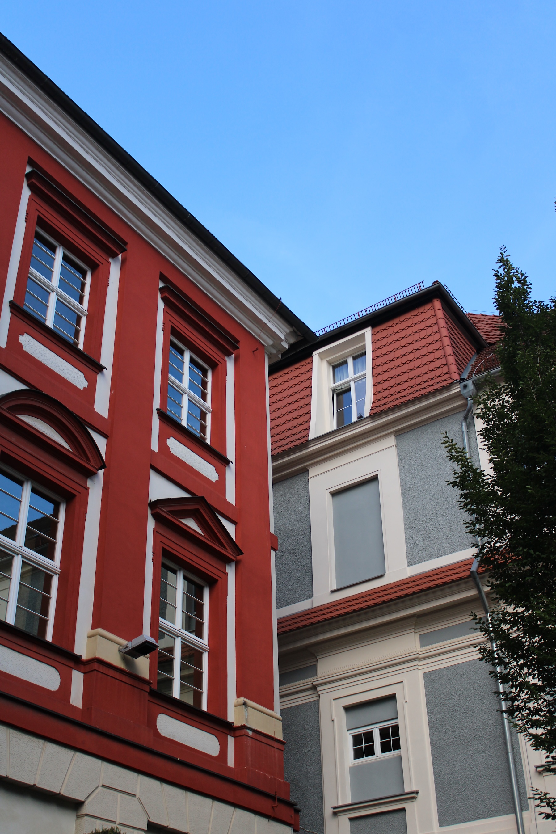 A red and grey building corner a perfectly blue sky